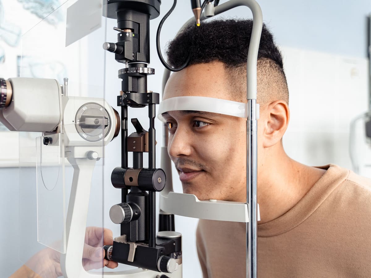 A patient resting his chin on a slit lamp during an eye examination
